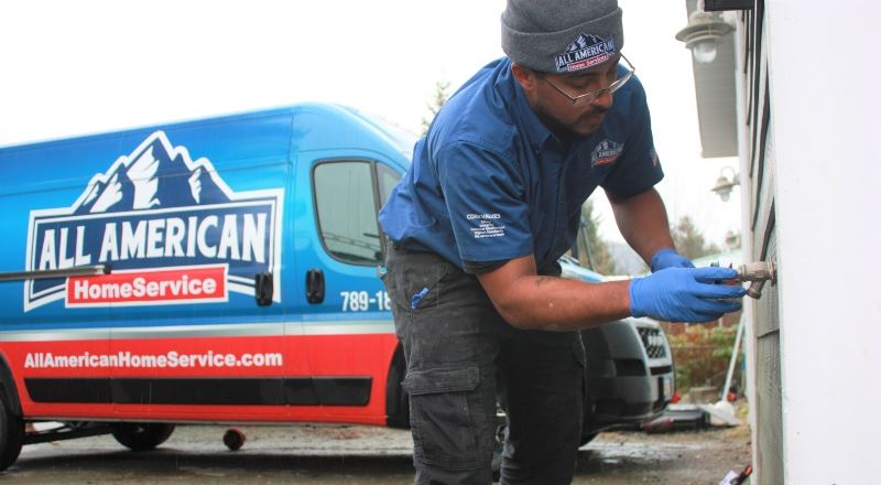 Plumbing technician installing nozzle on side of house